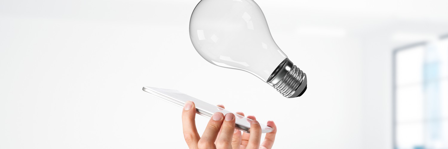 Hand som håller en mobiltelefon riktad mot en glödlampa