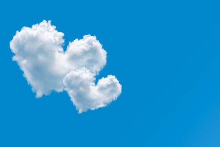 Couple of heart shaped clouds on a clear blue sky background. Concept of love and romance. Pair of cloud hearts in sky. Valentine's day design element. Greeting card with copy space. Symbol of care.