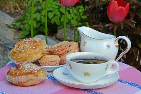 Framdukat fika; bullar och kaffe i en blommig kaffekopp