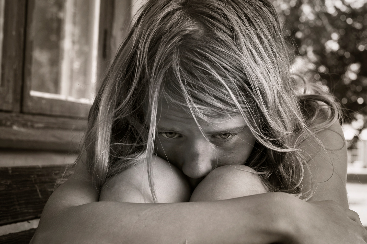 Portrait of a sad young girl holding herself in black and white.