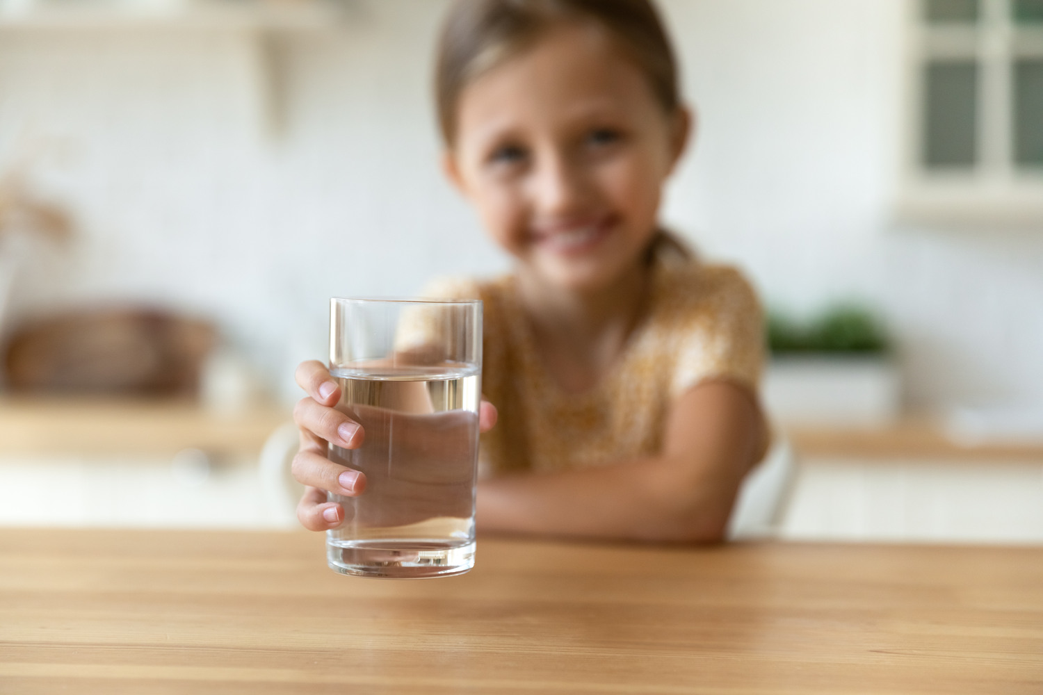 Flicka som håller fram ett glas med vatten
