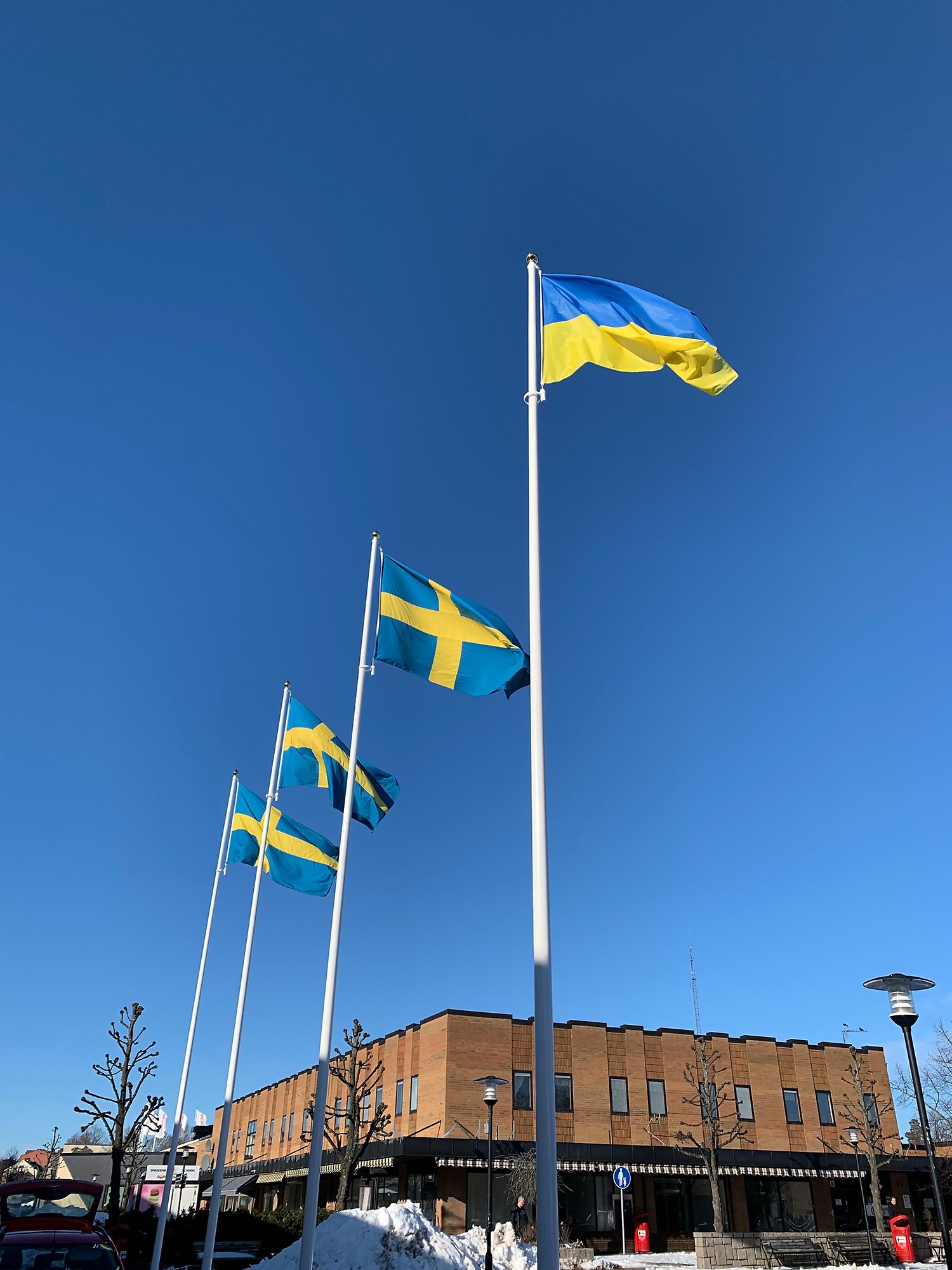 Flaggning på Hammartorget med tre svenska flaggor och en ukrainsk flagga